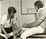 Trainer Assessing Football Players Leg by Fort Hays State University Athletics