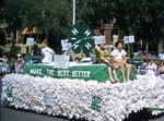 A boy and two girls are riding on a decorated float representing the Halstead Progressive 4-H Club in Newton