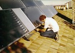 Man Mounting Solar Collectors On a Roof