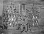 Three Men with Rifles in Front of Bird Carcasses