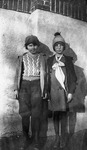 A boy and a girl are posing in front of a masonry school building.