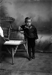 Box 7, Neg. No. 2806A: Boy Standing Next to a Chair by William R. Gray