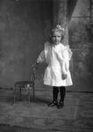 Box 16, Neg. No. 12071-2: Girl Standing by a Chair