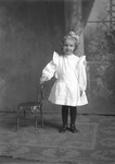 Box 16, Neg. No. 12071-3: Girl Standing by a Chair