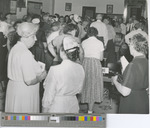 A Crowd of Older Men and Women Gathered around Tables Mingling in the 1950s.