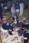 Team Members Sign Certificates on the Floor by Fort Hays State University Athletics
